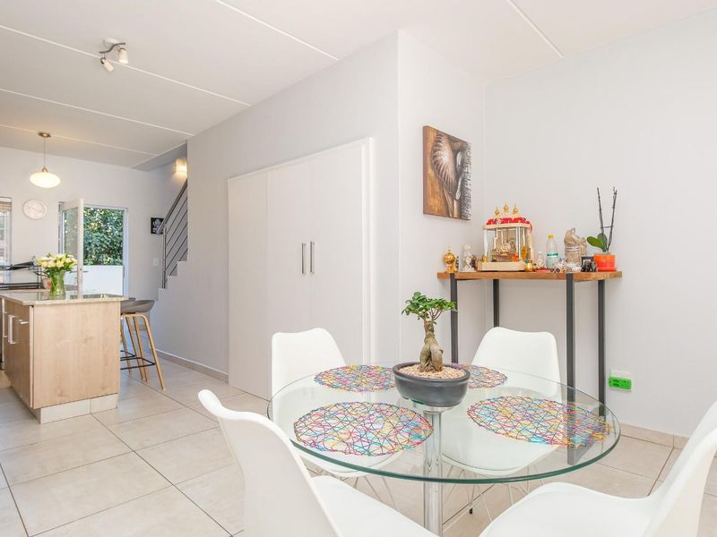Open plan living and dining area featuring tiled flooring, a modern kitchen island, and a staircase leading to the upper level.