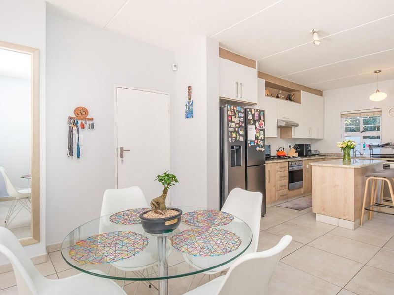 Open-plan kitchen and dining area featuring modern cabinetry, a central kitchen island, and tiled flooring with direct access to the outdoor space.