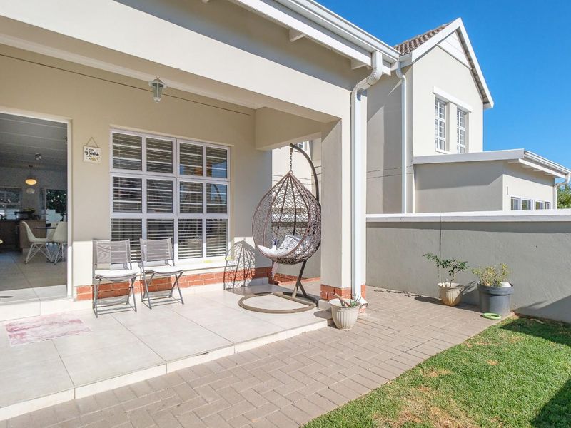A well-maintained covered patio featuring tiled flooring, brick paving, and direct access to the interior living space through a sliding door.