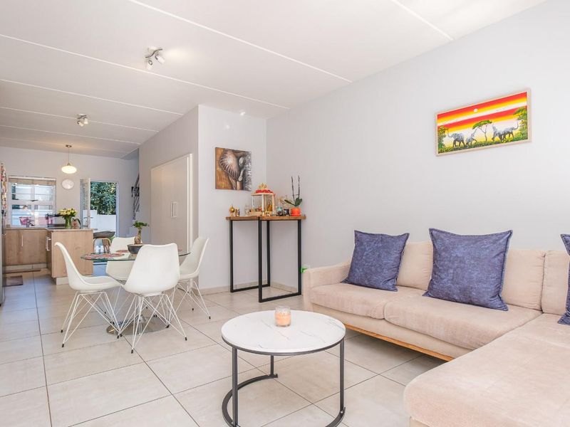 An open-plan living and dining area featuring neutral tiled flooring and a seamless transition into a functional kitchen space.