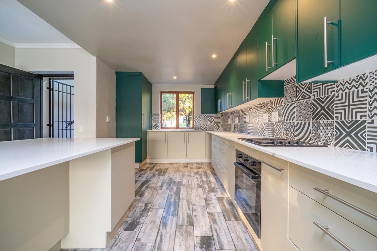 Modern kitchen featuring two-tone cabinetry, stone countertops, built-in oven, gas hob, and decorative patterned tile backsplash with wood-look tiled flooring.