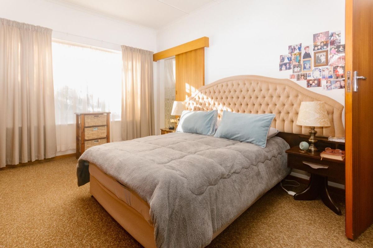 A well-lit bedroom featuring carpeted flooring, coving, and a built-in sliding door wardrobe.