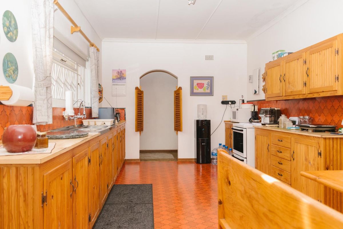 A functional kitchen featuring traditional wooden cabinetry, a tiled backsplash, and a double sink, offering a classic layout with potential for modern updates.