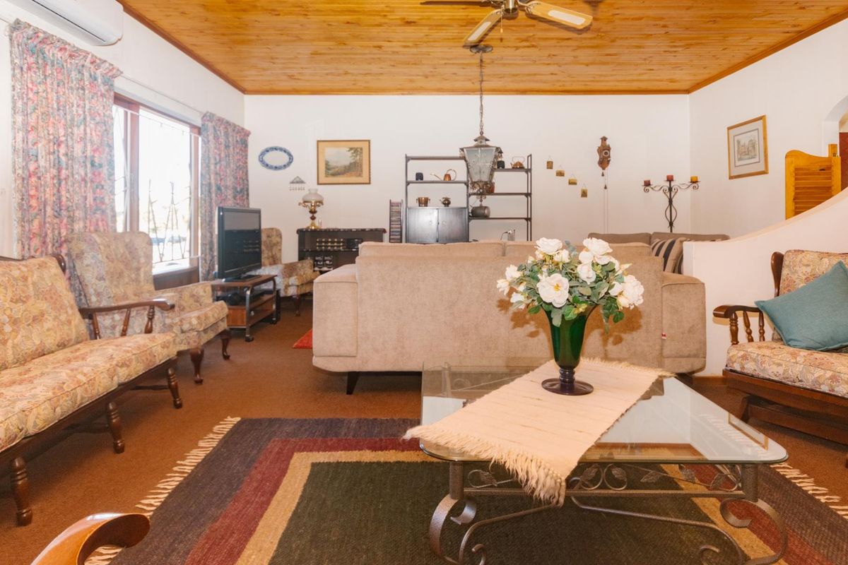 A living room featuring a timber-paneled ceiling, ceiling fan, and split-system air conditioning, providing a comfortable and functional space.