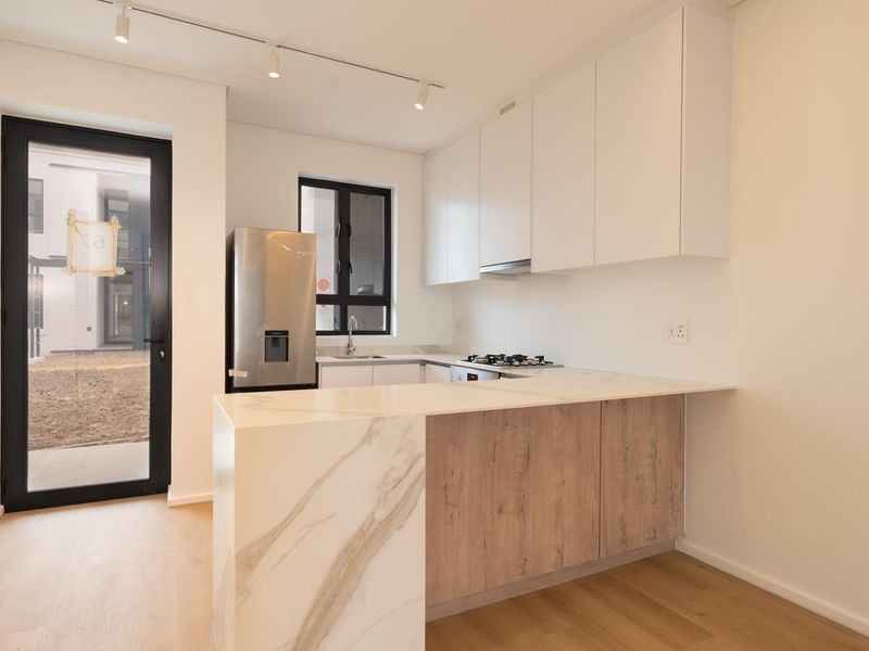 Modern kitchen featuring marble-look stone countertops, wood-grain cabinetry, built-in gas hob, and direct access to an outdoor area.