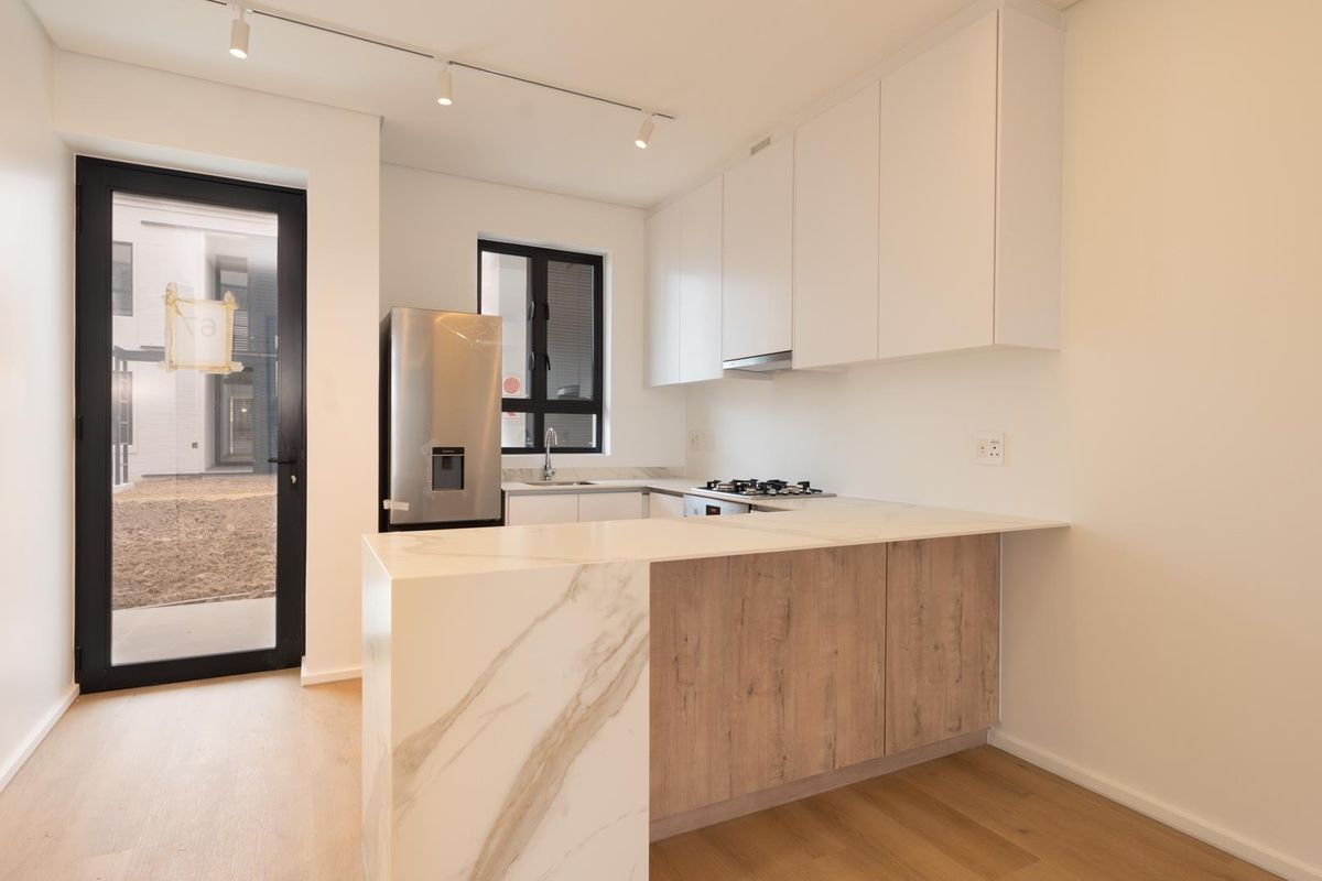 Modern kitchen featuring marble-look stone countertops, wood-grain cabinetry, built-in gas hob, and direct access to an outdoor area.