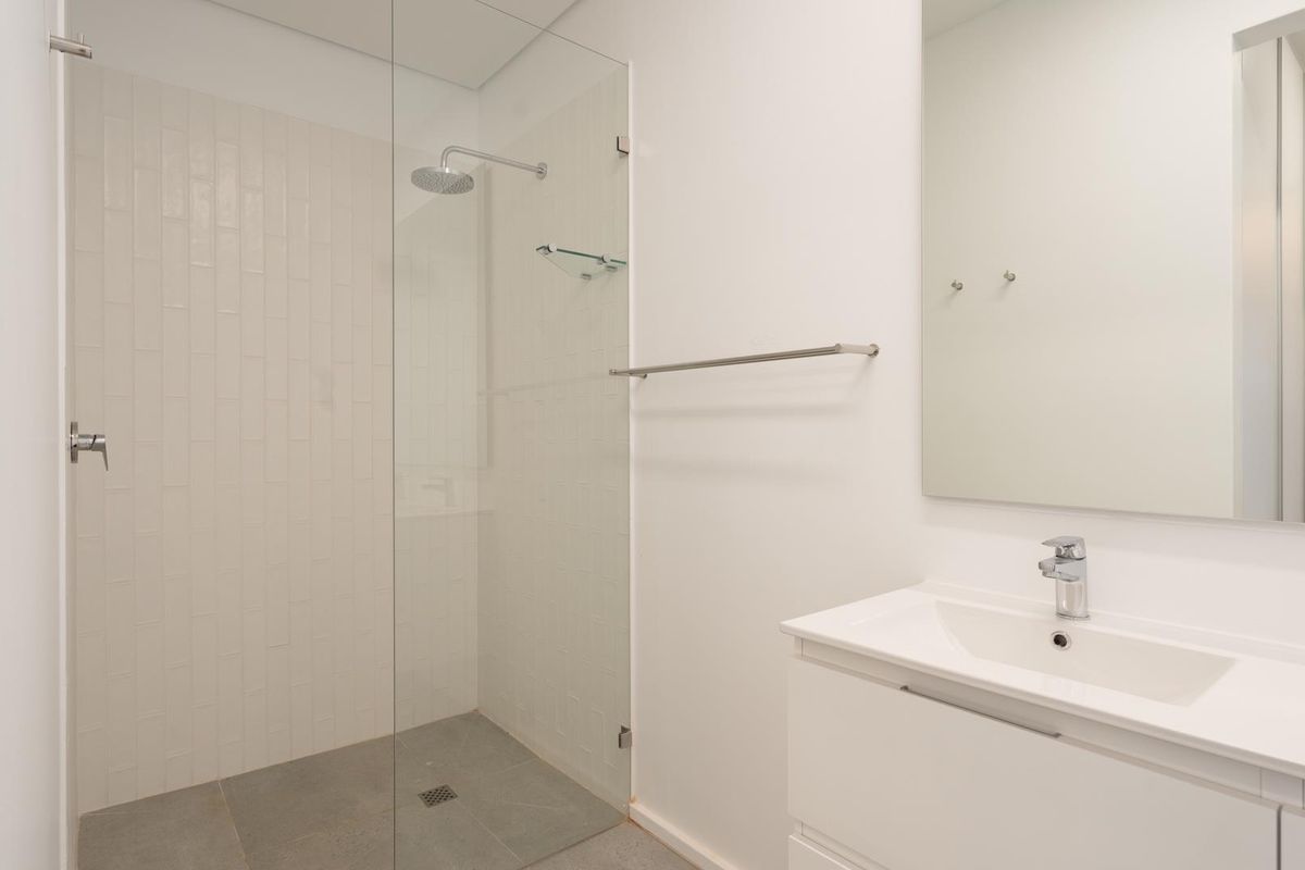 Modern bathroom featuring a walk-in shower with a glass screen, subway tile detailing, and a sleek vanity with an integrated basin and mirror.
