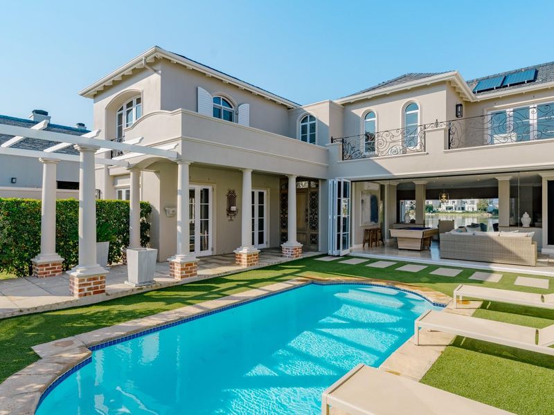 A beautifully maintained rear exterior featuring a swimming pool, covered patio with pergola, and seamless indoor-outdoor flow through large bi-fold doors.