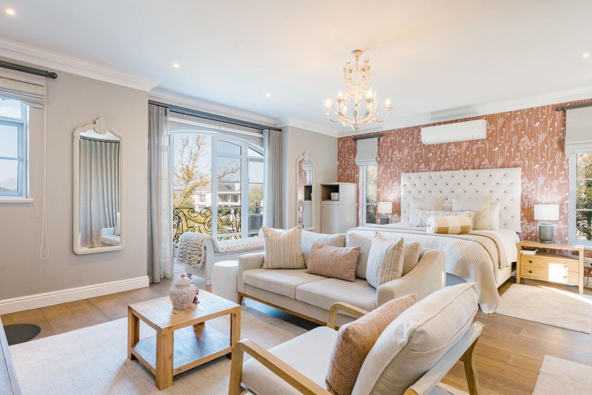Spacious bedroom featuring timber flooring, recessed lighting, a split-system air conditioner, and direct access to a private balcony through sliding glass doors.