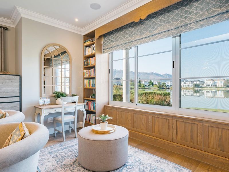 A well-appointed living area featuring custom built-in bookshelves, timber window seat cabinetry, and large windows offering scenic lake and mountain views.