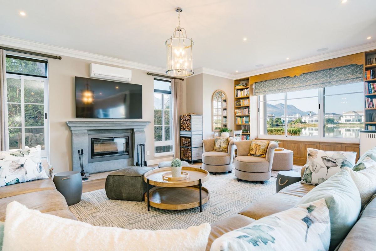 Spacious living room featuring a stone fireplace, built-in bookshelves, recessed lighting, and large windows with scenic views.