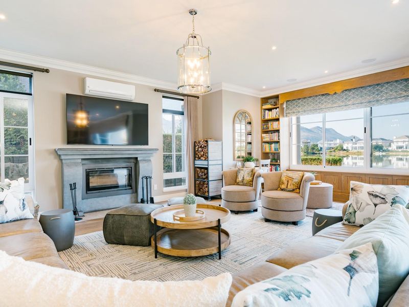 Spacious living room featuring a stone fireplace, built-in bookshelves, recessed lighting, and large windows with scenic views.