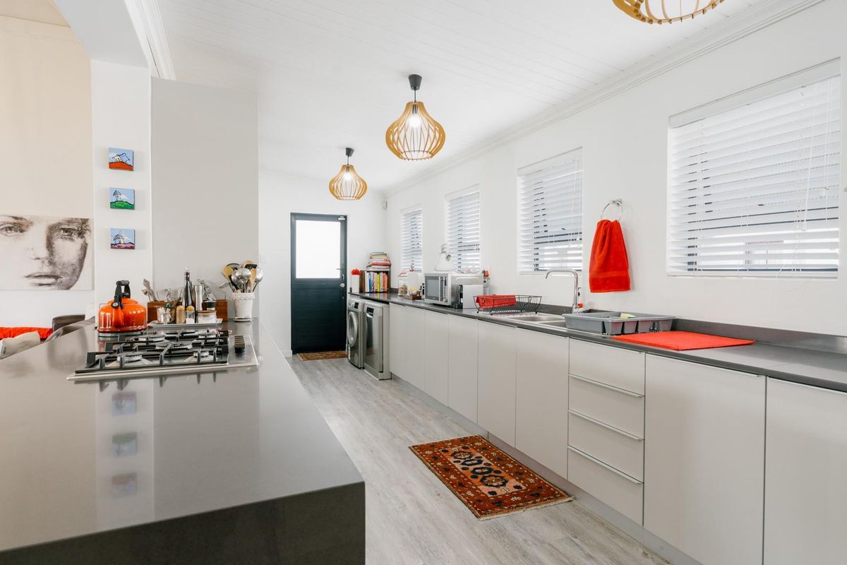 Modern kitchen featuring sleek cabinetry, stone countertops, a gas cooktop, and ample natural light through multiple windows.