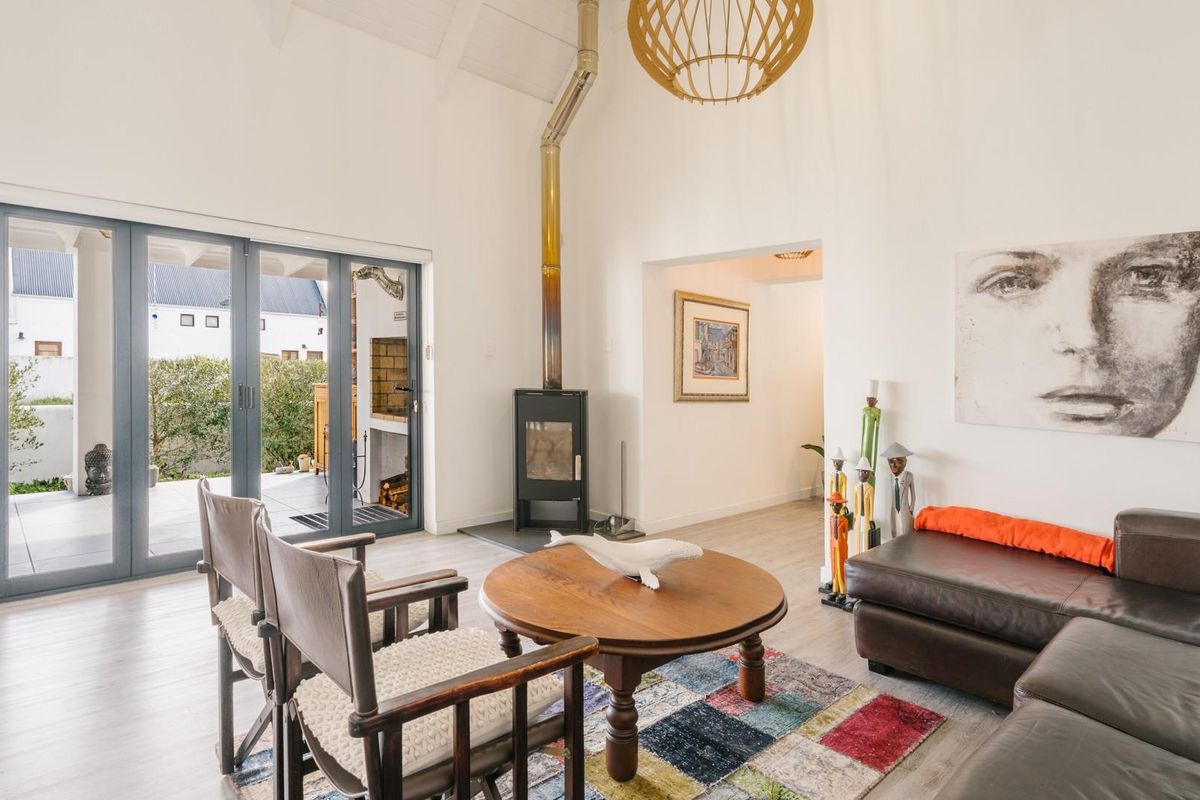 Bright living room featuring a vaulted ceiling, modern freestanding fireplace, and bi-fold doors providing seamless access to the outdoor patio area.