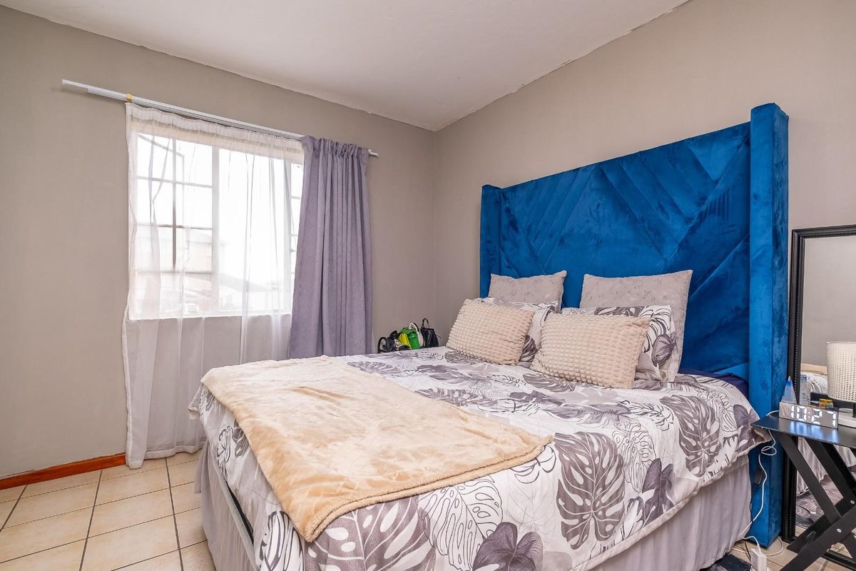 A bedroom featuring tiled flooring and a window with a curtain rod, providing natural light to the space.
