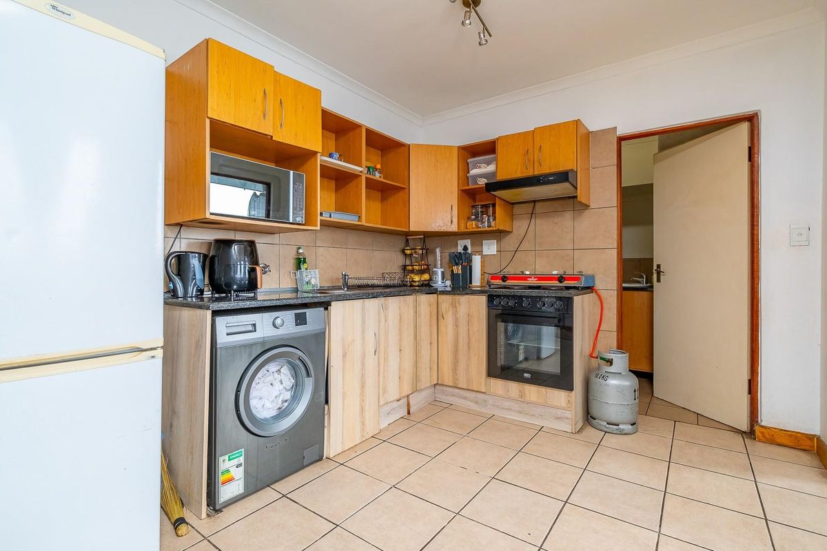 Functional kitchen featuring laminate cabinetry, granite countertops, built-in oven with gas hob, and tiled flooring, offering a practical layout for daily meal preparation.