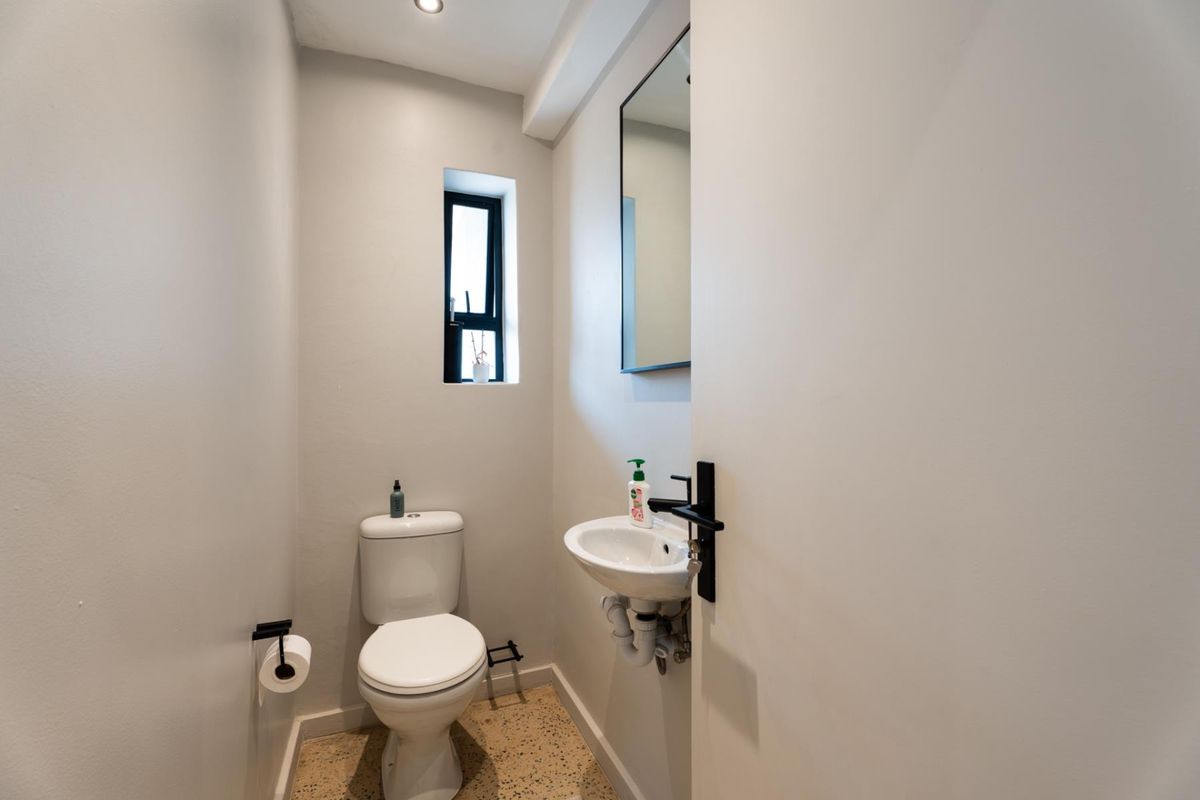 A compact, modern guest bathroom featuring a wall-mounted basin, toilet, and terrazzo flooring with neutral wall finishes.