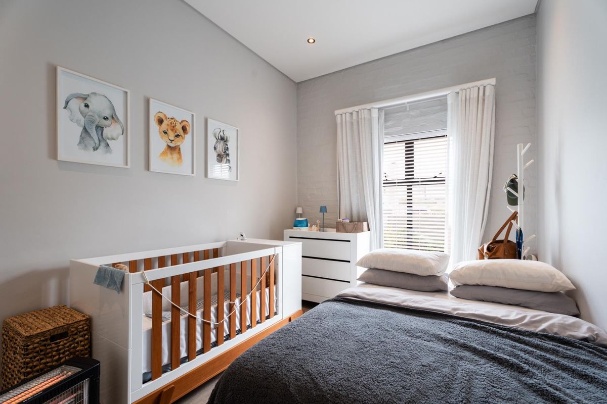 A well-maintained bedroom featuring painted brick walls, recessed lighting, and window treatments including venetian blinds and curtains.