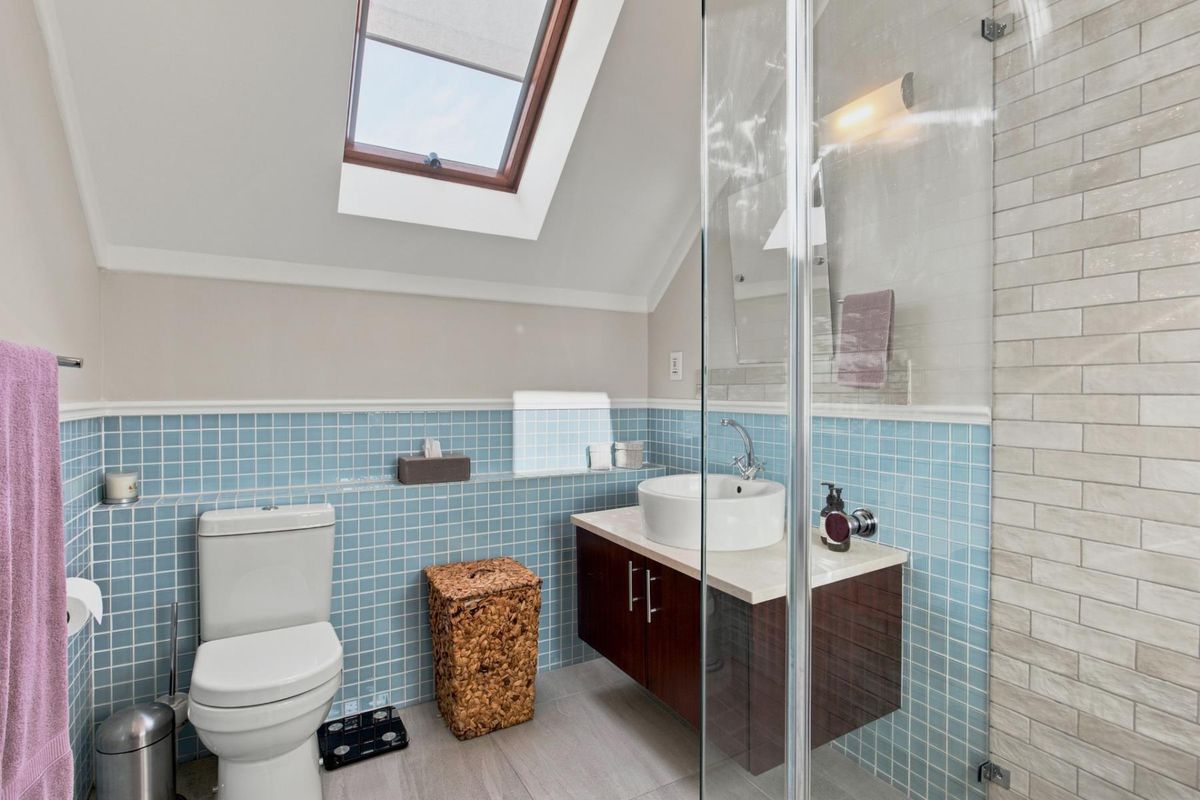 Modern bathroom featuring a floating vanity with vessel sink, glass-enclosed shower, and a skylight providing natural light.