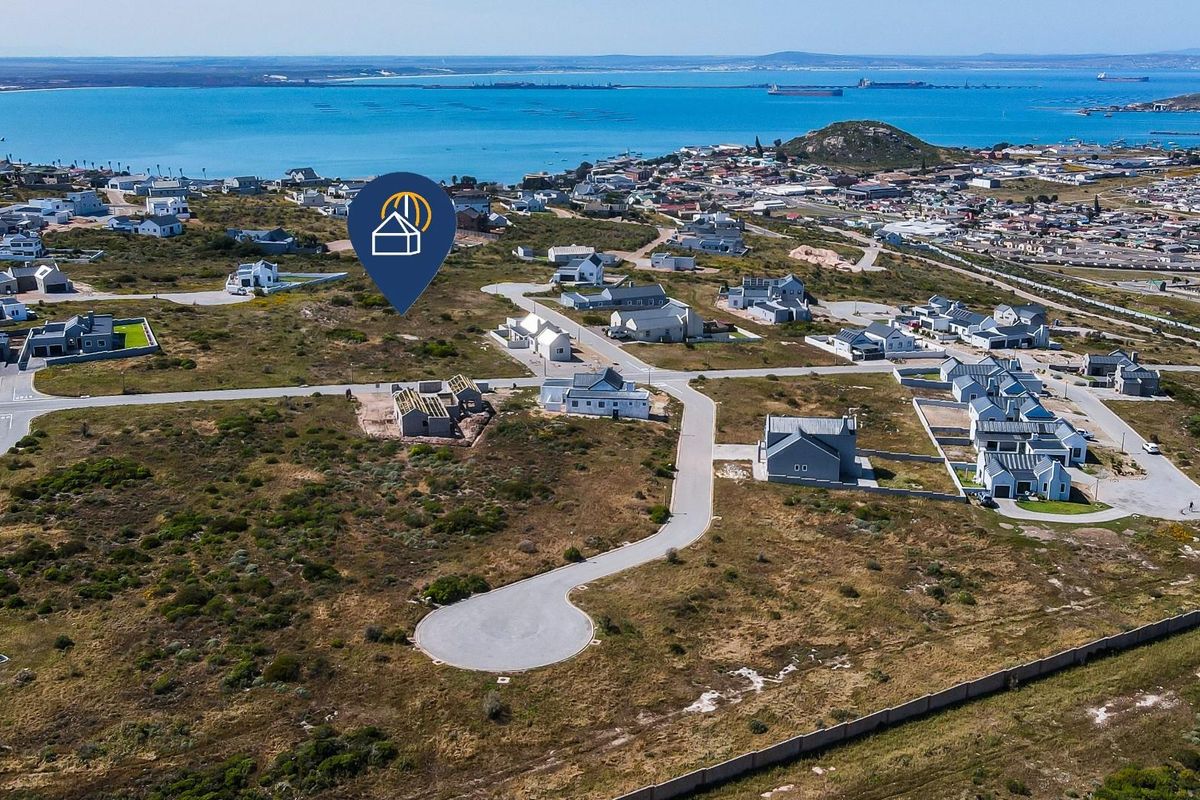Aerial view of a residential development site featuring paved roads and coastal proximity in a quiet neighborhood setting.