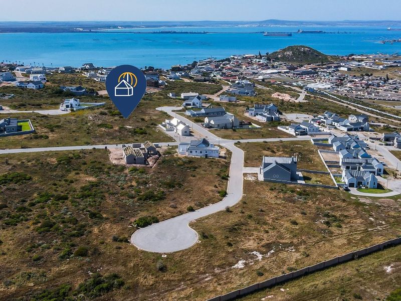 Aerial view of a residential development site featuring paved roads and coastal proximity in a quiet neighborhood setting.