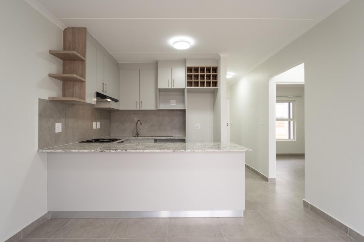 Modern kitchen featuring granite countertops, built-in cabinetry with integrated wine rack, and a breakfast bar, finished with neutral tiling and clean lines.