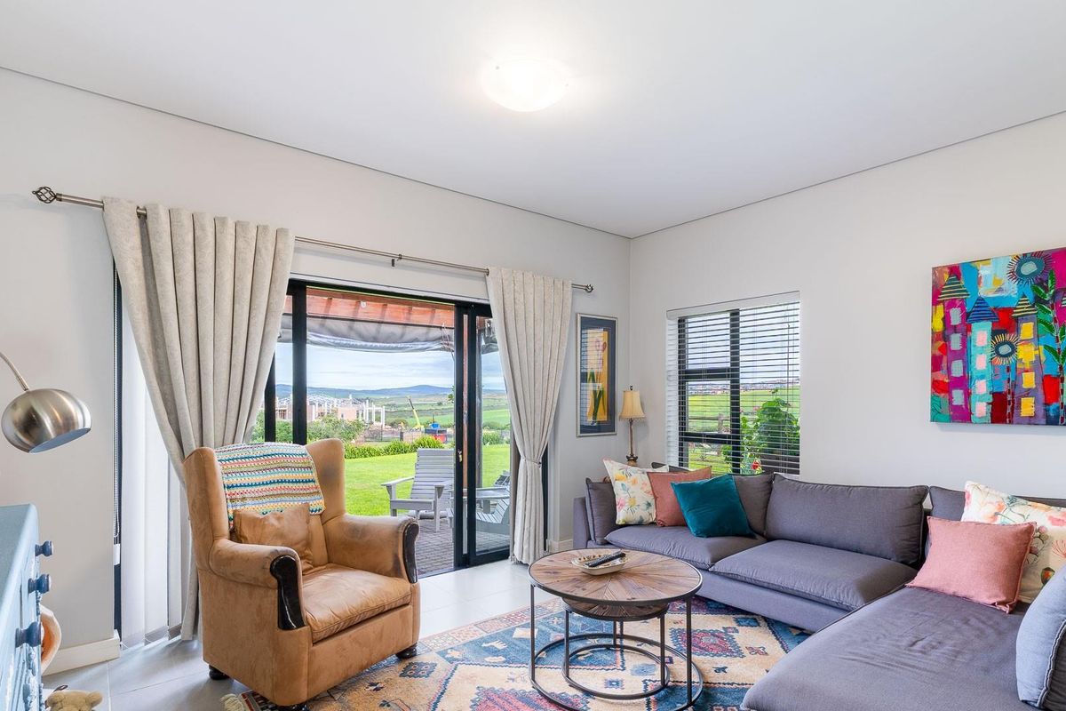 A bright and well-maintained living room featuring tiled floors, large sliding glass doors leading to a patio, and ample natural light.