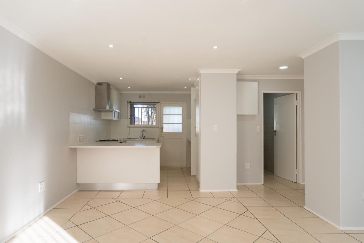 A clean, open-plan kitchen featuring neutral cabinetry, tiled flooring, and integrated appliances, offering a bright and functional space ready for personalization.