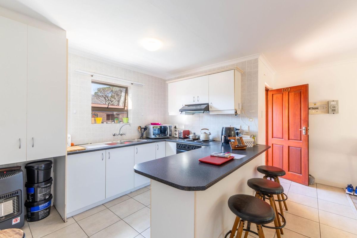 A functional kitchen featuring white cabinetry, dark laminate countertops, a breakfast bar, and tiled finishes, providing a practical layout for daily use.