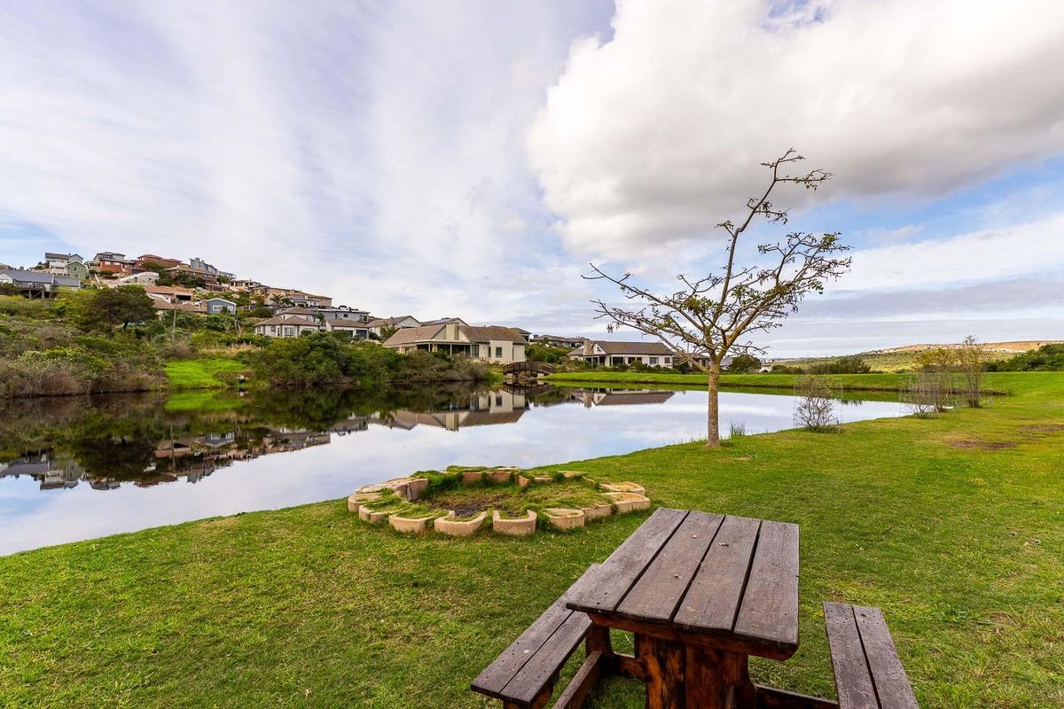 A scenic view of a tranquil pond surrounded by landscaped green lawns and residential properties in the background.