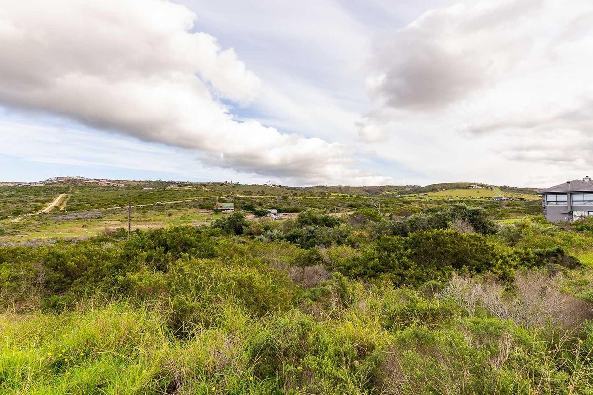 A wide-angle view of the vacant residential land, showcasing the natural landscape, surrounding vegetation, and distant rolling hills.