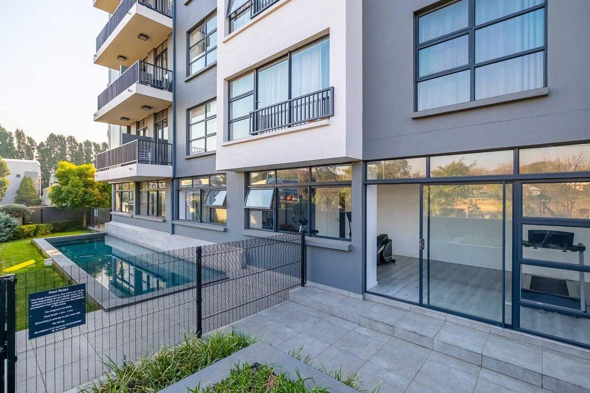 Exterior view of a modern apartment building featuring a swimming pool, ground floor patio access, and multiple levels of private balconies.
