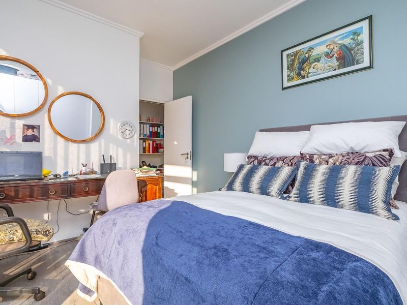 A well-lit bedroom featuring laminate flooring, a built-in cupboard, and a feature wall, offering a comfortable and functional living space.