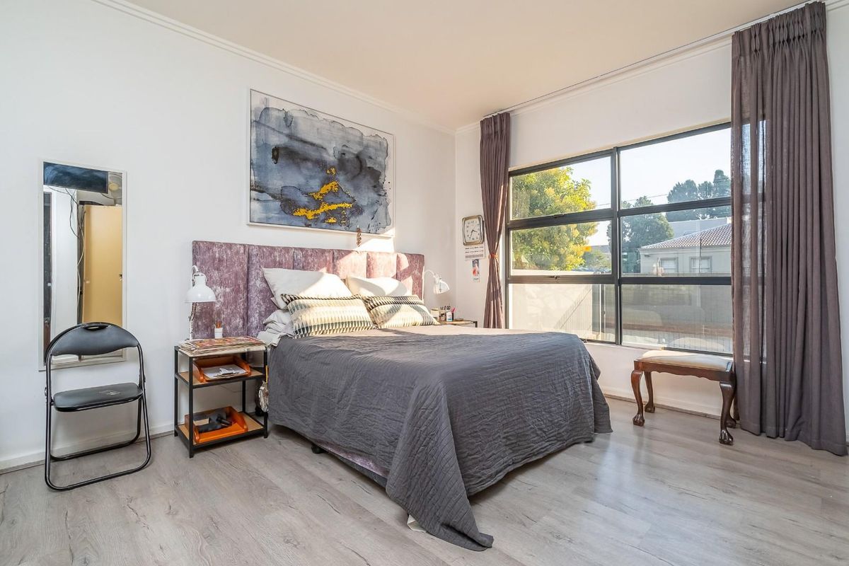 A bright bedroom featuring large windows that provide ample natural light and modern laminate flooring throughout the space.