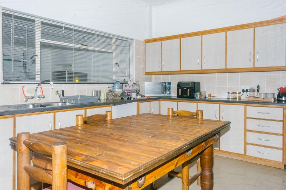 A functional kitchen featuring laminate cabinetry, tiled backsplash, and a stainless steel sink, offering a dated aesthetic ready for modern updates.