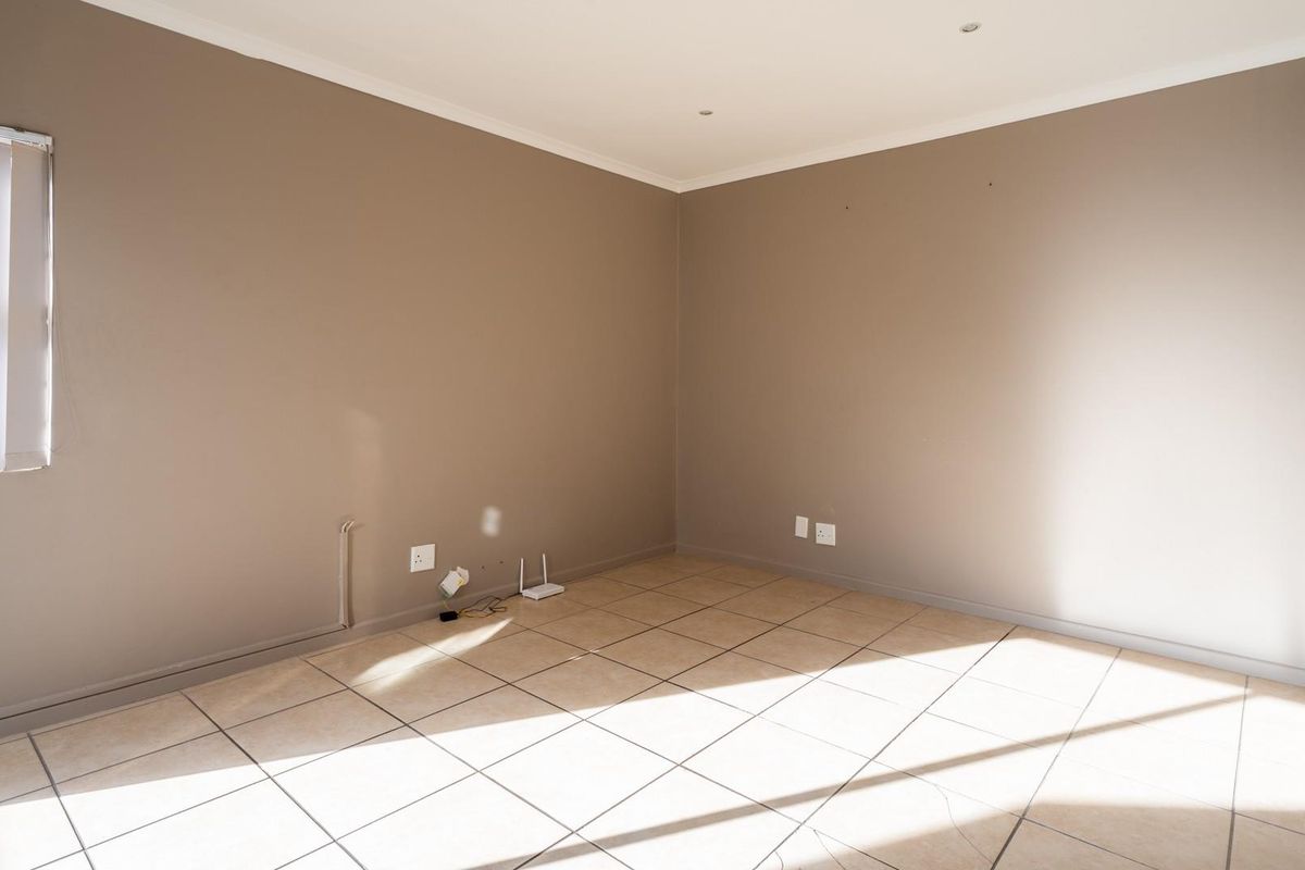 A bright, empty bedroom featuring neutral wall tones, tiled flooring, and recessed downlighting, offering a clean canvas for personalization.
