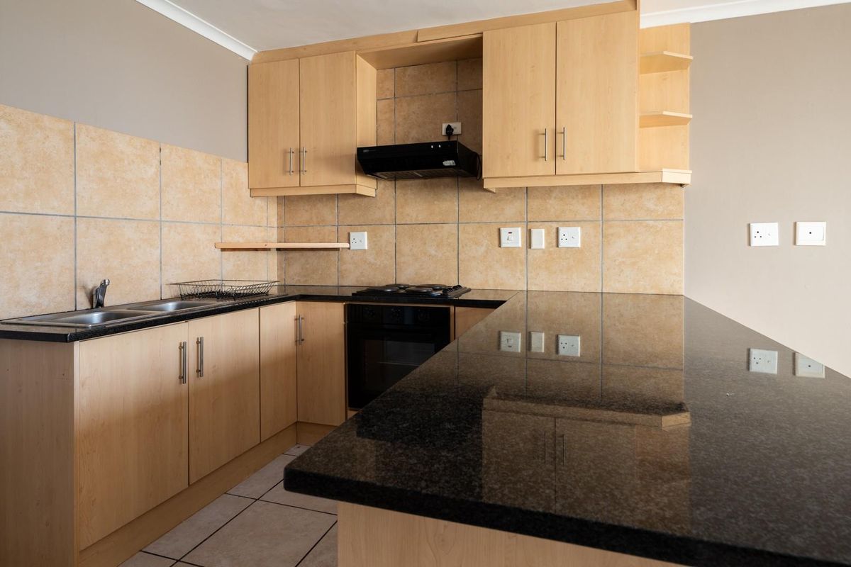 A functional kitchen featuring light wood cabinetry, dark granite countertops, a built-in oven, gas hob, and a tiled backsplash.