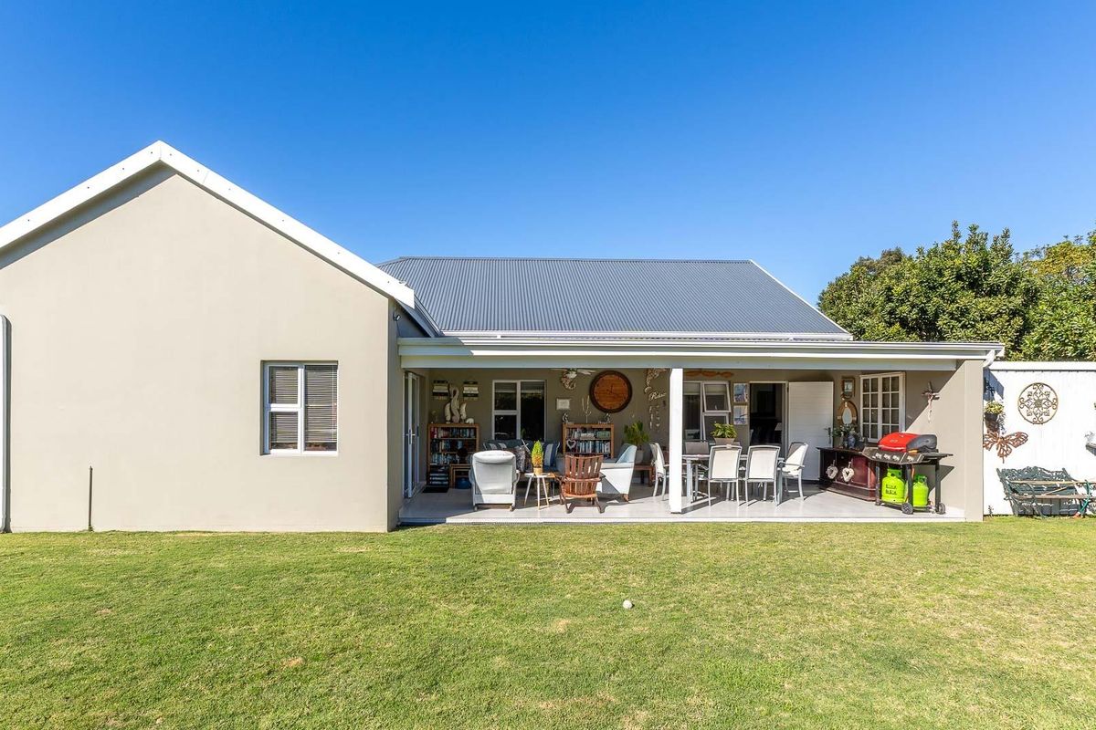 Rear view of the house featuring a spacious covered patio area, tiled flooring, and a well-maintained lawn.