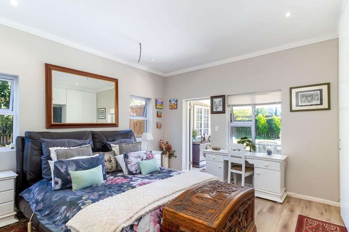 A well-maintained bedroom featuring laminate flooring, built-in cupboards, and direct access to an adjoining patio area through a glass door.
