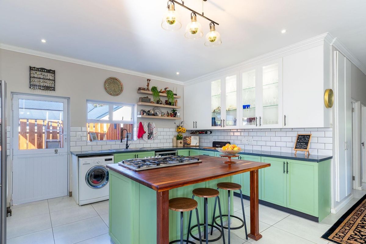 A bright, modern kitchen featuring a central island with a gas hob, subway tile backsplash, and ample storage with glass-front cabinetry.