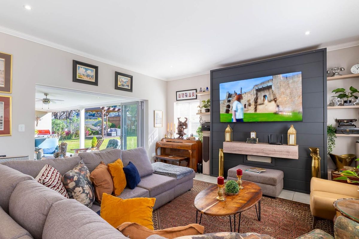 Spacious living room featuring a dark feature wall, recessed lighting, and large bi-fold doors providing seamless access to the rear garden.
