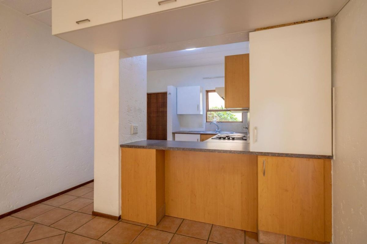 A functional kitchen featuring laminate cabinetry, a breakfast bar, and tiled flooring, offering a practical layout with potential for modern updates.