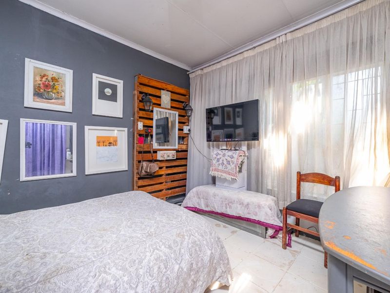 A bedroom featuring tiled flooring, curtained windows with security bars, and a dark accent wall.