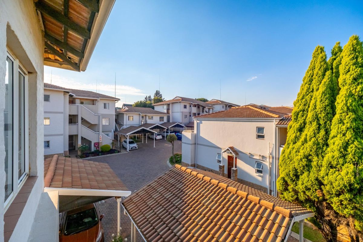 Elevated view of the apartment complex courtyard featuring paved driveways, covered carports, and multi-story residential buildings with tiled roofs.
