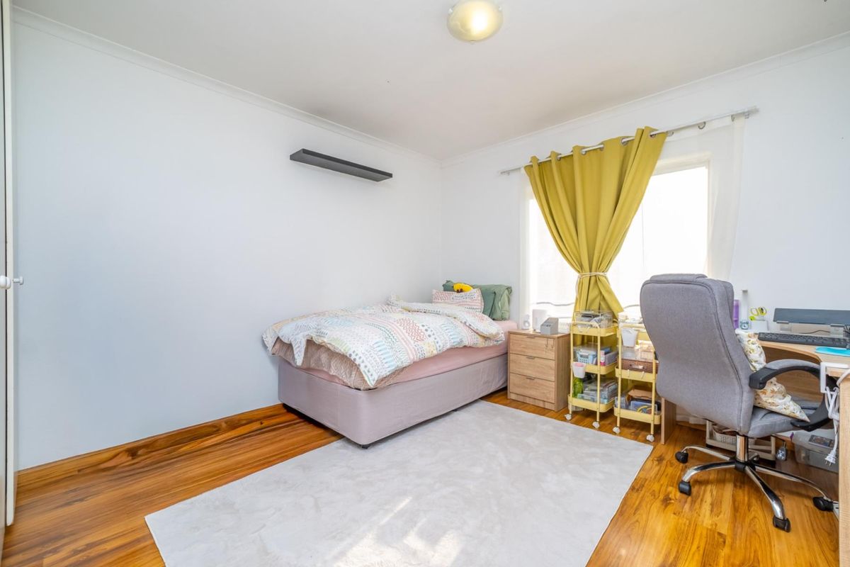 A well-lit bedroom featuring polished timber flooring, neutral walls, and coving, providing a comfortable and functional living space.