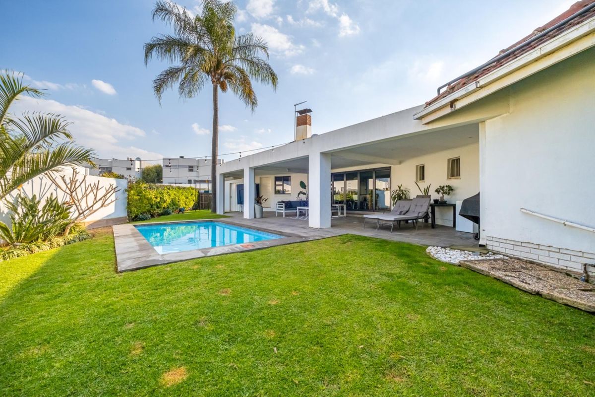 Rear exterior view featuring a swimming pool, a spacious covered patio area, and a well-maintained garden.