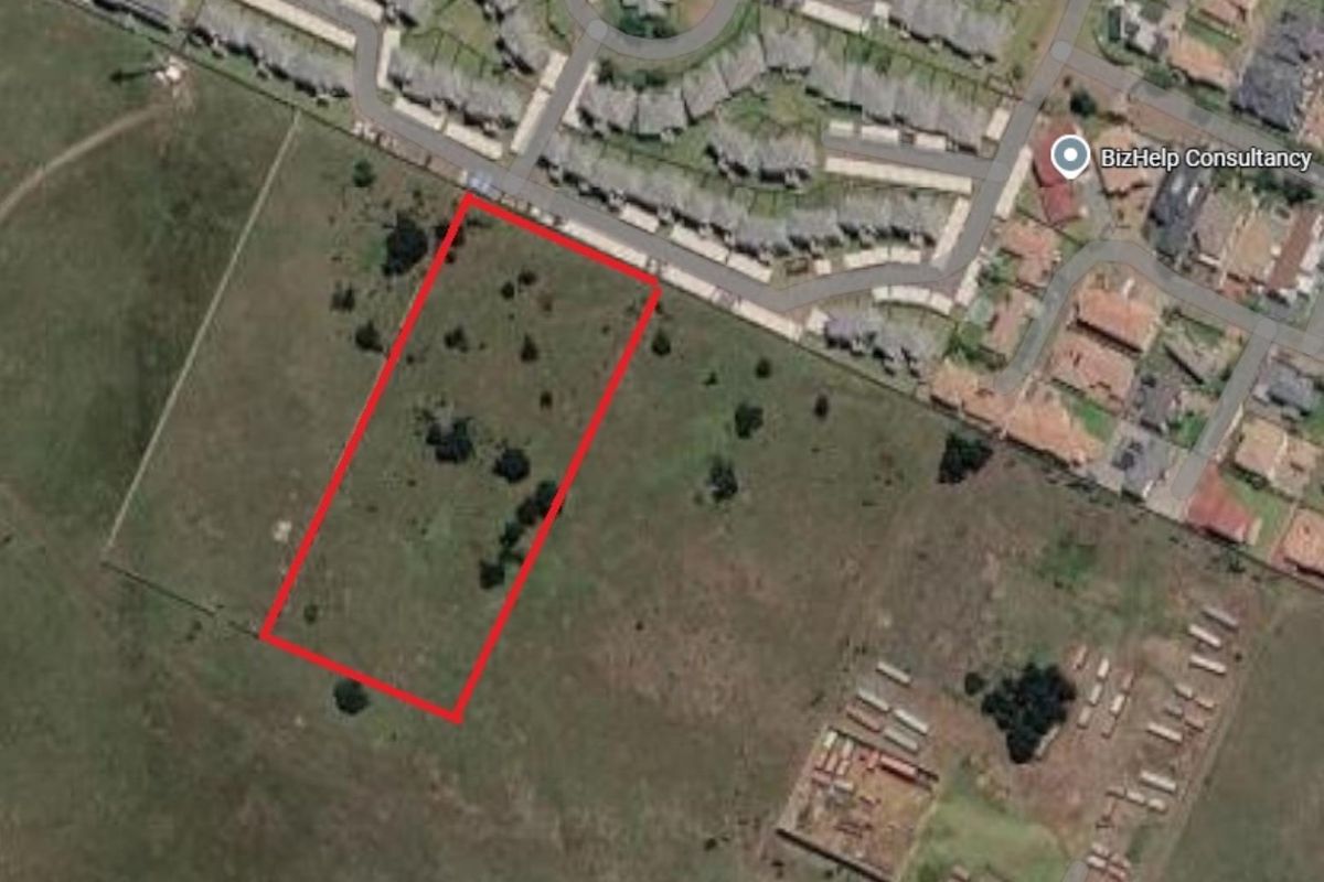 Aerial view of a vacant residential plot outlined in red, situated within a developed estate area.