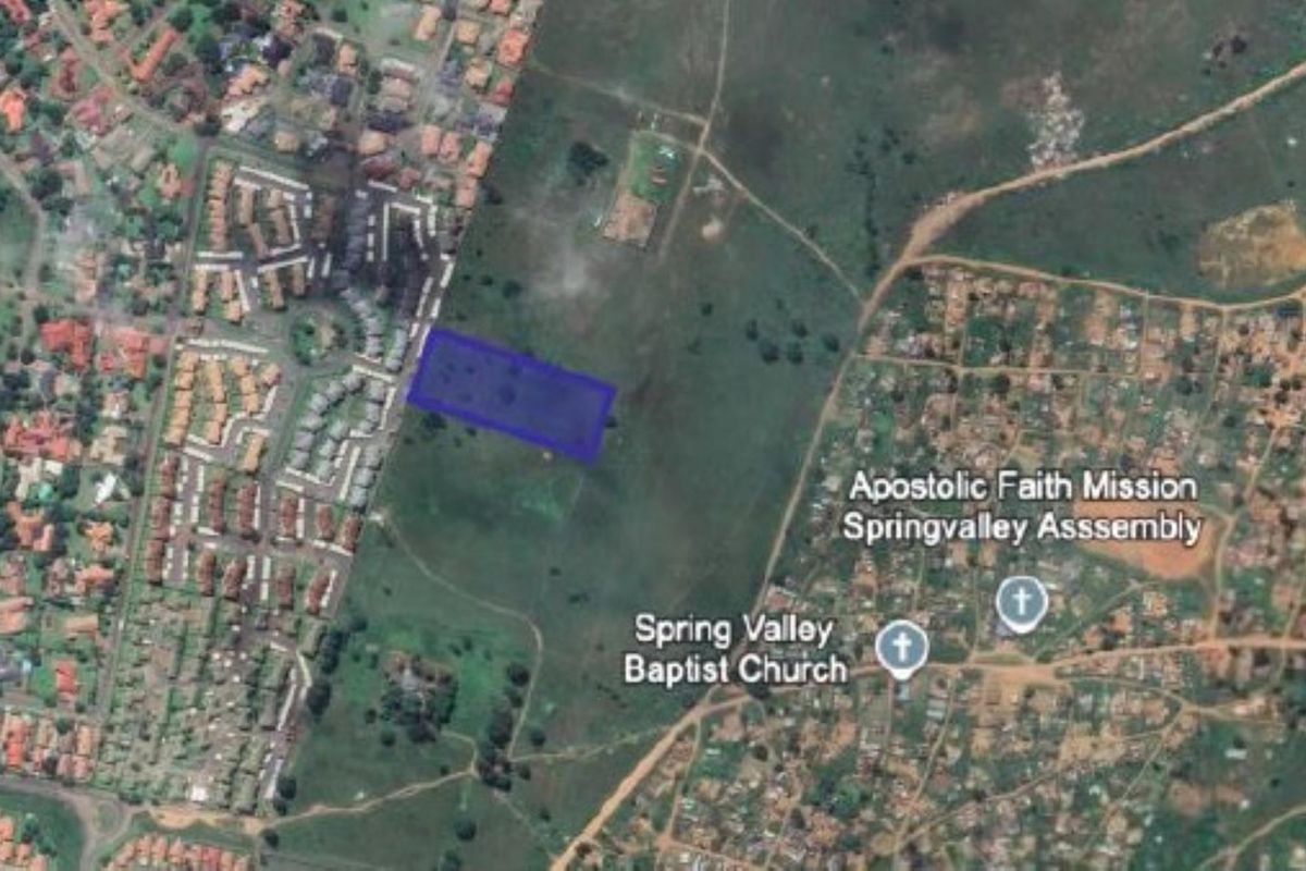 Aerial satellite view showing the designated vacant residential land plot highlighted in blue within the surrounding neighborhood context.
