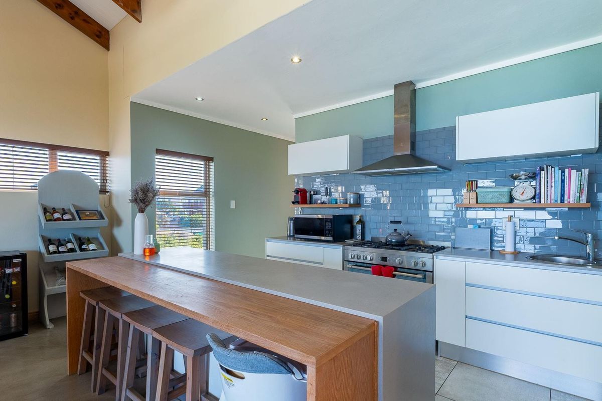 Modern kitchen featuring a central island, gas stove with extractor fan, subway tile backsplash, and high vaulted ceilings with exposed timber beams.