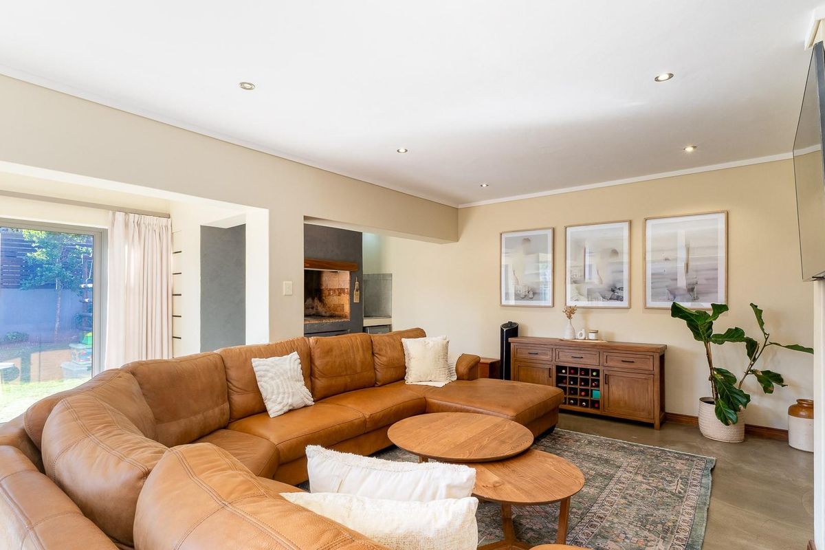 Spacious living room featuring concrete flooring, recessed lighting, and a built-in fireplace, with direct access to the outdoor garden area through sliding glass doors.